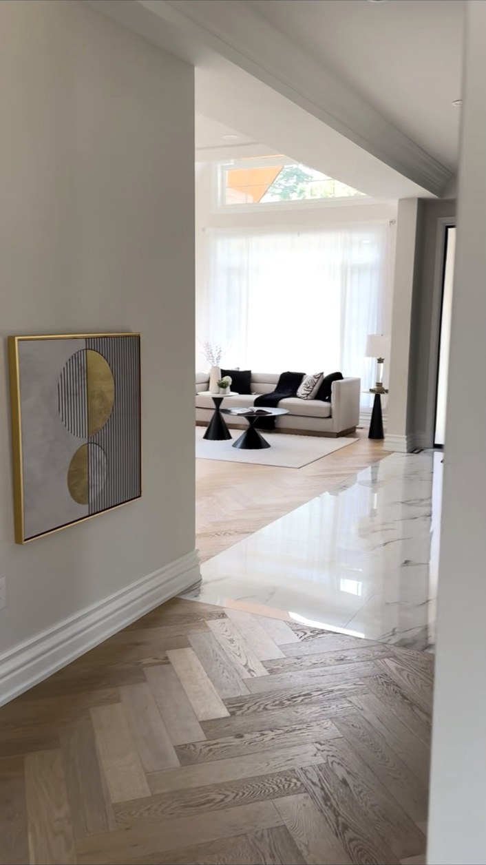 Hallway connecting wood flooring and a white stone entry